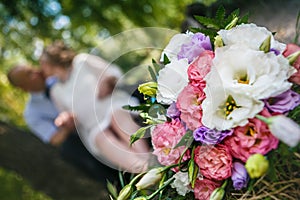 Bouquet of eustoma and roses and kissing couple on the soft background