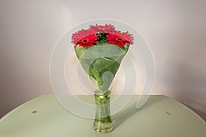 Bouquet of five red gerberas scientific name Gerbera in a glass vase on the table. Romantic background, Valentines day concept.