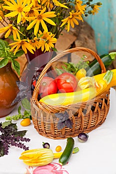 Bouquet of flowers and basket with autumn crop of seasonal vegetables