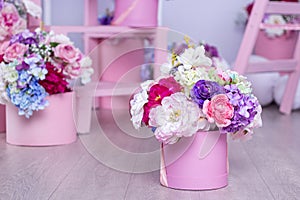 A bouquet of flowers in a basket on the background of floral arrangements in the studio. Beautiful decorations