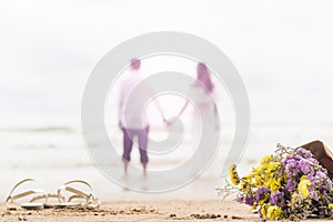 bouquet of flowers on beach with couple blurred bright background