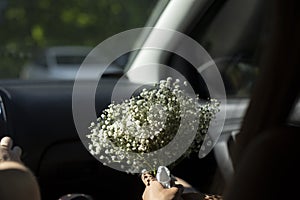 Ð­Bouquet of flowers in car. Bride's bouquet is in hands of girl. White flowers in hand