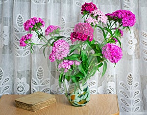 A bouquet of flowers carnations on the table in a glass vase.