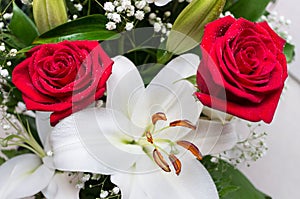 Bouquet of flowers close-up on a white background. Two red roses and a white lily