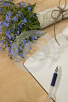 A bouquet of flowers forget-me, notebook and pen on the wooden t