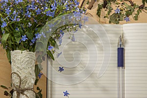 A bouquet of flowers forget-me, notebook and pen on the wooden t
