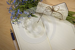 A bouquet of flowers forget-me, notebook and pen on the wooden t