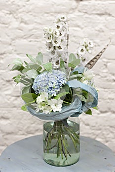 A bouquet of flowers is in a glass vase on the table . blue flowers. Bouquet with hydrangea close-up.