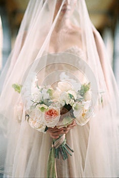 Bouquet of flowers in the hands of a bride in a veil. Close-up