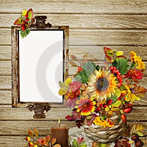 A bouquet of flowers, leaves and berries in a wicker vase, photo frame or text on the wooden background