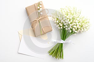 Bouquet of flowers lily of the valley, gift box and blank greeting card on white background