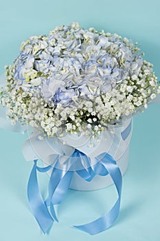 Bouquet of flowers made of hydrangeas and gypsophila in a white box with a bow.