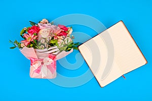 Bouquet of flowers with a notebook and pen on a blue background. place for an inscription. blue background, Bouquet of colorful
