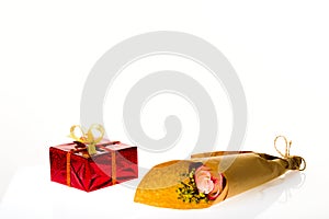 Bouquet of flowers in parchment paper and wrapped gift on a whit