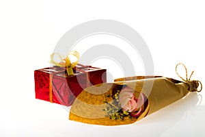 Bouquet of flowers in parchment paper and wrapped gift on a whit