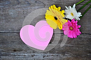 Bouquet of flowers with pink paper heart on wood