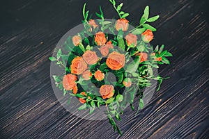 Bouquet of flowers on the retro dark wood. Red roses on a wooden dark table. Roses in vintage style on wooden background