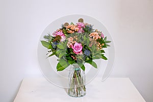 Bouquet of flowers with roses and daisies in a glass vase on the table