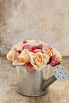 Bouquet of flowers in silver watering can, wooden background