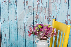 Bouquet of flowers in vintage vase sitting on yellow chair