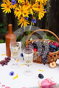 Bouquet of flowers, wine, glasses and grapes against the background of an old fence