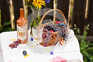 Bouquet of flowers, wine, glasses and grapes against the background of an old fence