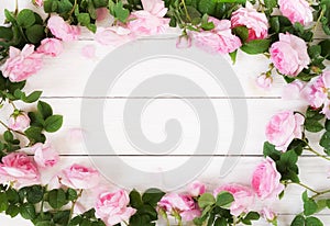 Bouquet frame of beautiful pink roses on white wooden background