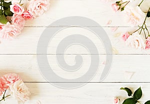 Bouquet frame of beautiful pink roses on white wooden background