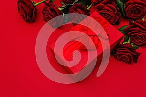 Bouquet of fresh burgundy roses and gift box on a matte red foamiran background