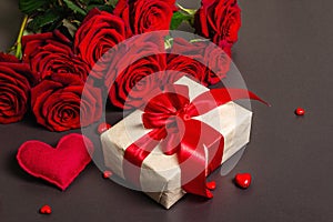 Bouquet of fresh burgundy roses  gift and festive hearts on a black stone concrete background