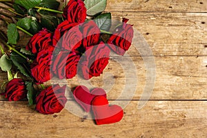 Bouquet of fresh burgundy roses and soft felt hearts on a vintage wooden background