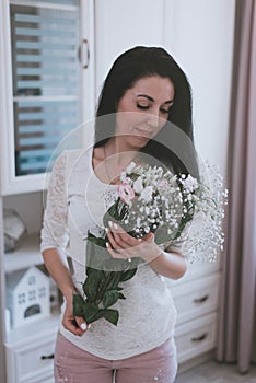 bouquet of fresh flowers in the hands of a girl in a white t-shirt and pink pants home photo session