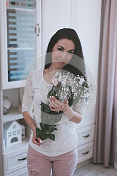 bouquet of fresh flowers in the hands of a girl in a white t-shirt and pink pants home photo session