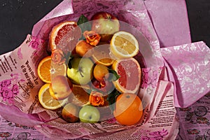 A bouquet of fresh fruits with citrus and roses wrapped in colorful wrapping paper. Fruit bouquet with fresh fruits and flowers.