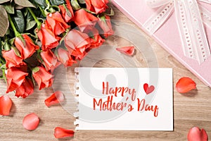 Bouquet of fresh pink red roses with gift on wooden background. Floral romantic arrangement with card text Happy Mother's Day