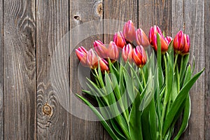 Bouquet of fresh pink tulips on a wooden background, top view.