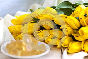 Bouquet of fresh yellow tulips close-up. Flowers in the interior on the background of the bed. Breakfast with coffee and homemade