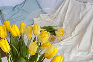 Bouquet of fresh yellow tulips close-up. Flowers in the interior on the background of the bed. Breakfast with coffee and homemade