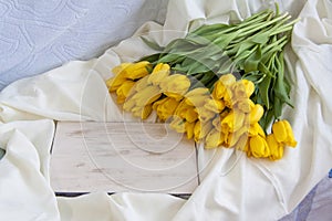 Bouquet of fresh yellow tulips close-up. Flowers in the interior on the background of the bed. Breakfast with coffee and homemade