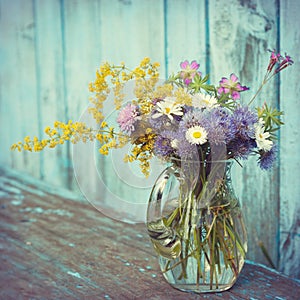 Bouquet of garden flowers and healing herbs in glass jug