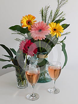 A bouquet of gerberas and two glasses of pink merlot