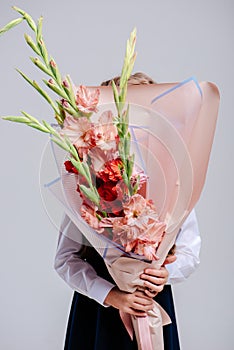 A bouquet of gladiolus in the hands of girl