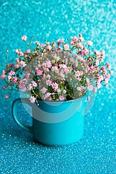 Bouquet of gypsophila in a blue mag on a blue glitter background