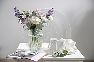 Bouquet of hackelia velutina, purple and white roses, small tea roses, matthiola incana and blue iris in glass vase is on the