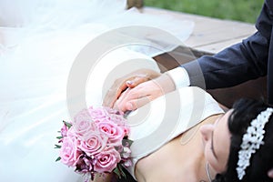 Bouquet and hands of the bride and groom with wedding rings