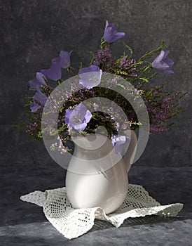 Bouquet of heather with bluebells in a white jug