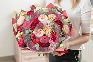 Bouquet of highly red coloured . beautiful luxury bunch of mixed flowers in womans hand. the work of the florist at a