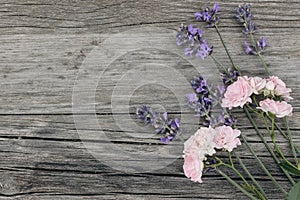 Bouquet of lavender flowers and little pink roses on old wooden table background. Decorative floral frame, web banner