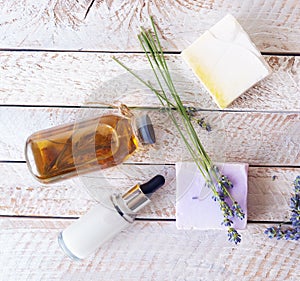 Bouquet of lavender flowers, soap, cream and aromatic oil on the table, light background, spa, natural cosmetics