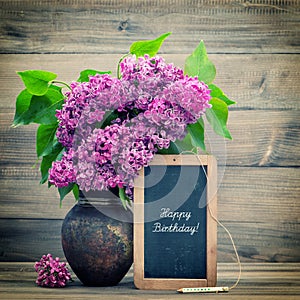 Bouquet of lilac flowers. blackboard with text Happy Birthday!